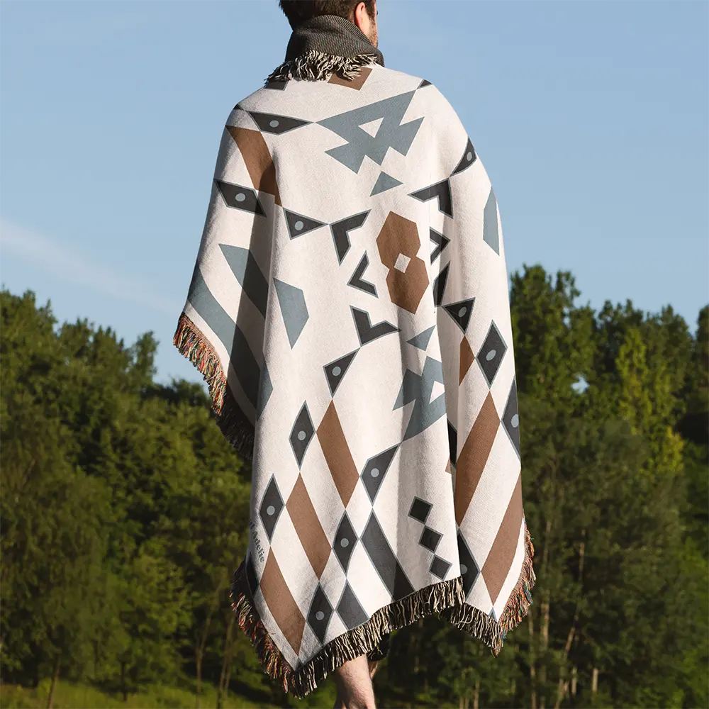 Wandering Warrior Blanket with a geometric pattern in blue, brown, and white worn by a person from behind.