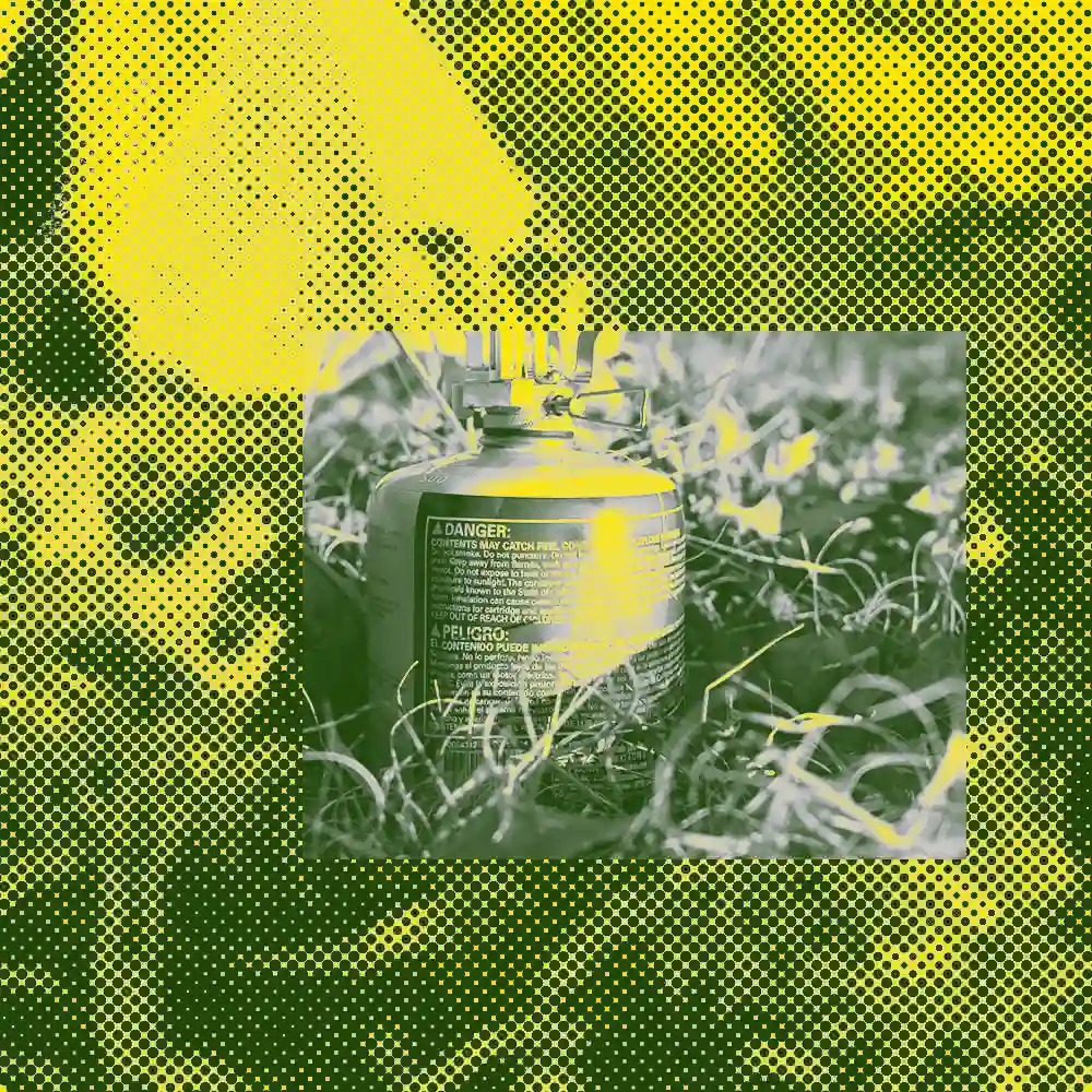 High-contrast Pop Art style image of an outdoor camping gas canister, rendered in a vibrant neon yellow and deep forest green color palette. The background features a heavy halftone dot pattern (Ben-Day dots) over abstract grass. The central canister clearly displays a bold "DANGER/PELIGRO" warning label, creating an industrial, vintage screen-printed aesthetic with a nomadic outdoor vibe.