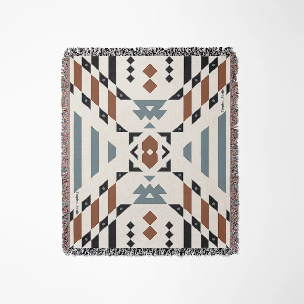 Tropical Adelie "Wandering Warrior" woven throw blanket featuring a symmetrical geometric Southwestern or tribal-inspired pattern in terracotta brown, slate blue, black, and cream, finished with colorful fringed edges.