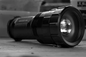 A flashlight glowing in the dark, a familiar tool in scary camping stories about nighttime sounds