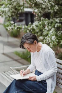 Woman practicing outdoor sketching in a sketchpad while drawing a nature-inspired artwork