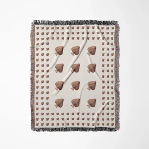 Cream woven cotton throw blanket with a grid pattern and brown mushroom motifs, dark fringe trim on all edges, photographed flat against a white background.